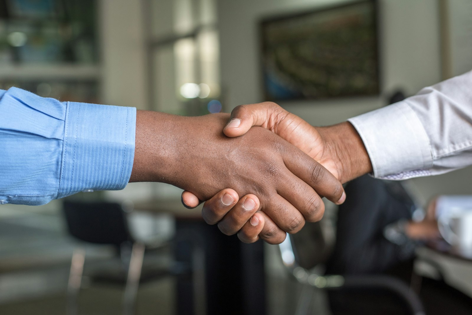 Two people shaking hands across a conference table