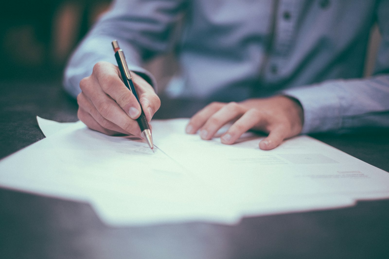 A person signing legal documents with a pen