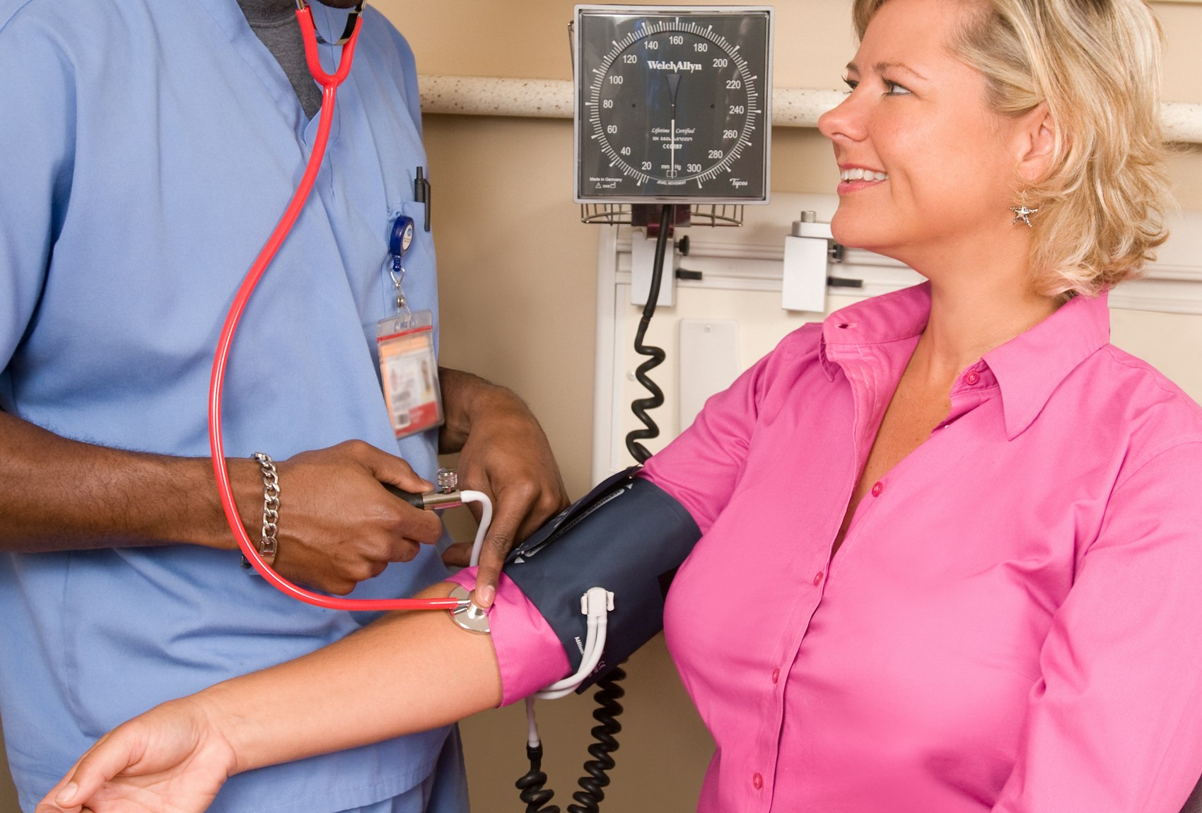 A nurse checking a smiling patient's blood pressure